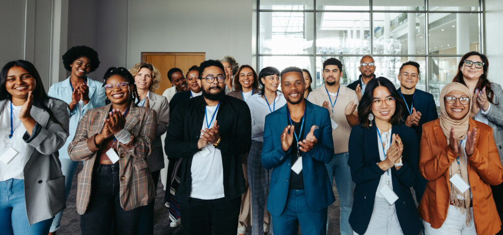 Diverse group of professionals at a business seminar clapping enthusiastically from a first person view. The audience is engaged and appreciative.