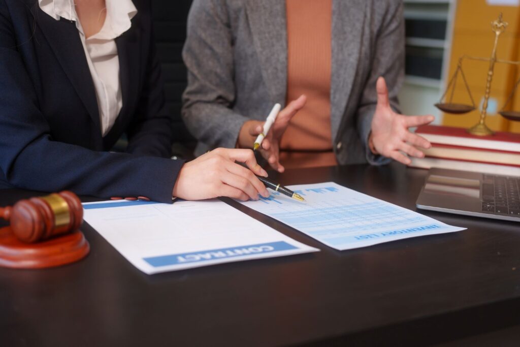 The hands of two lawyers are visible as they sit at a desk reviewing a contract.