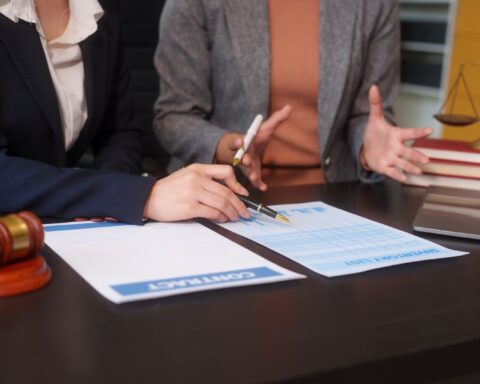 The hands of two lawyers are visible as they sit at a desk reviewing a contract.