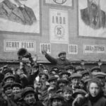 A black and white archival shot of a crowd in Amsterdam prior to World War II. A man in the middle is waving.