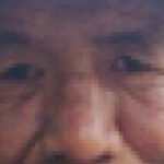 A pixelated image of an elderly Indigenous man's face. Only his nose, eyes, cheeks, and ears are visible with the line of a blue hat at the top of the frame.