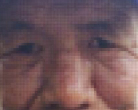 A pixelated image of an elderly Indigenous man's face. Only his nose, eyes, cheeks, and ears are visible with the line of a blue hat at the top of the frame.