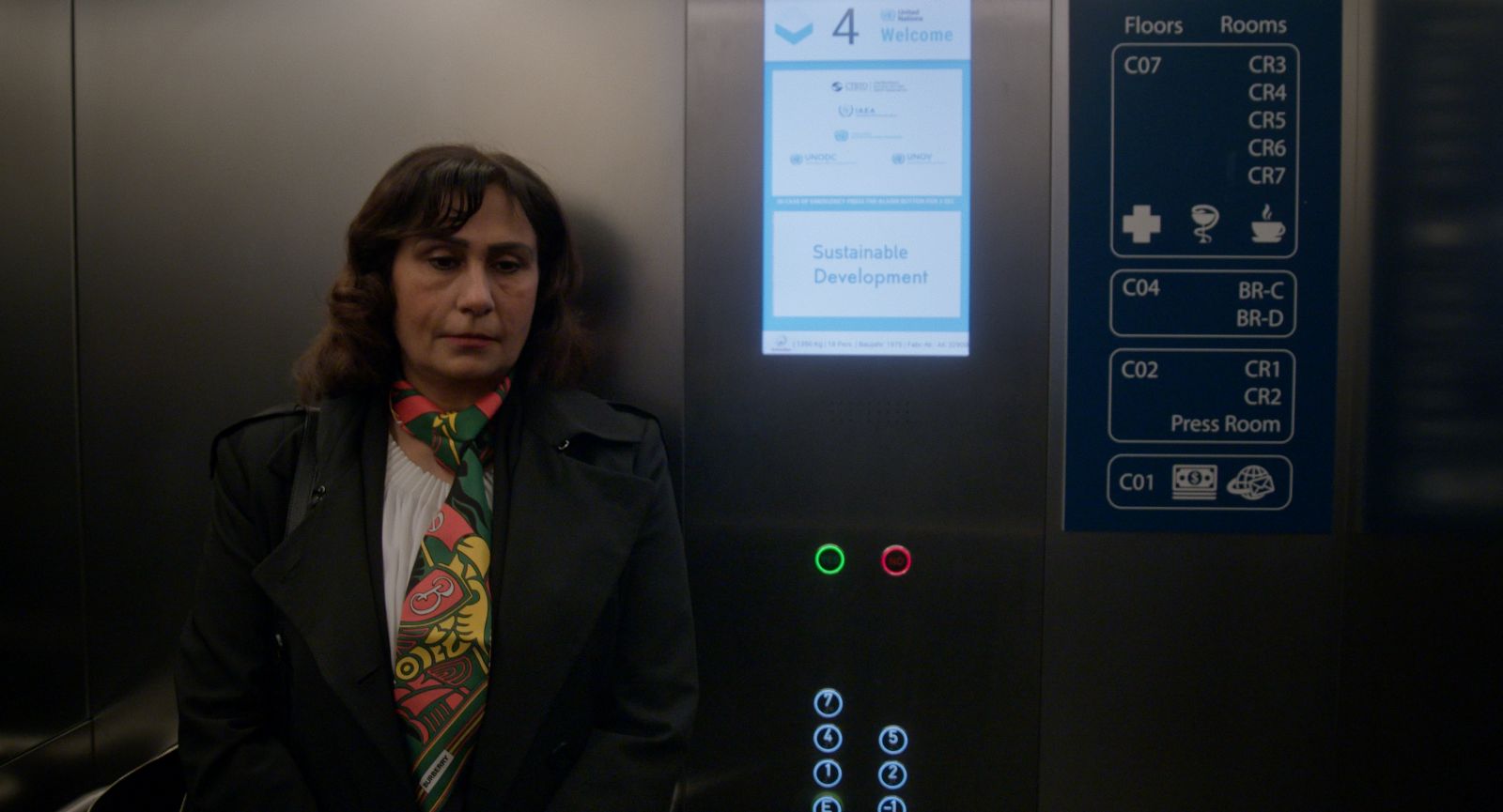 Manizha Bakhtari, an Afghan woman, stands in an elevator. She is wearing a dark suit with a pink and yellow checkered scarf.