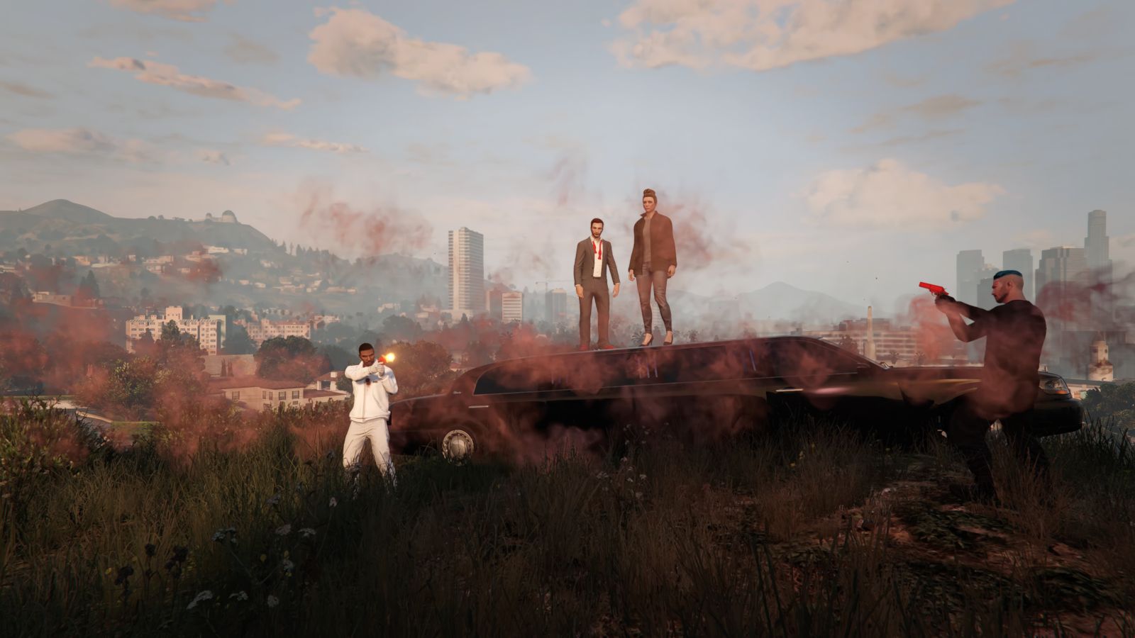 Four players are pictured in the video game Grand Theft Auto. Two stand atop a hill, and then there is a player on either side of them. The players to the sides have their guns drawn.