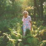 Agatha standing in her garden with a ray of sunlight shining over her and her plants