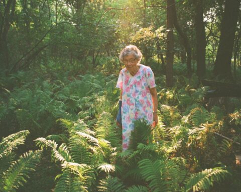 Agatha standing in her garden with a ray of sunlight shining over her and her plants
