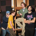 five actors portraying the band Pavement pose with director Alex Ross Perry. They are all wearing 1990s' style t-shirts and dress.