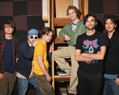 five actors portraying the band Pavement pose with director Alex Ross Perry. They are all wearing 1990s' style t-shirts and dress.