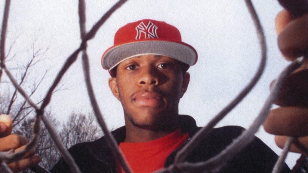 A slightly bottom-up view of Lenny Cooke holding a basketball net.