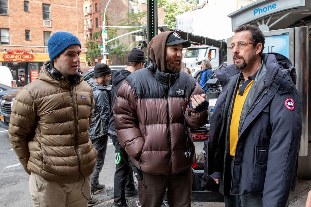 Three men stand outside in New York City preparing for a film shoot. They are three white guys with brown hair. They are wearing winter jackets and talking to each other.