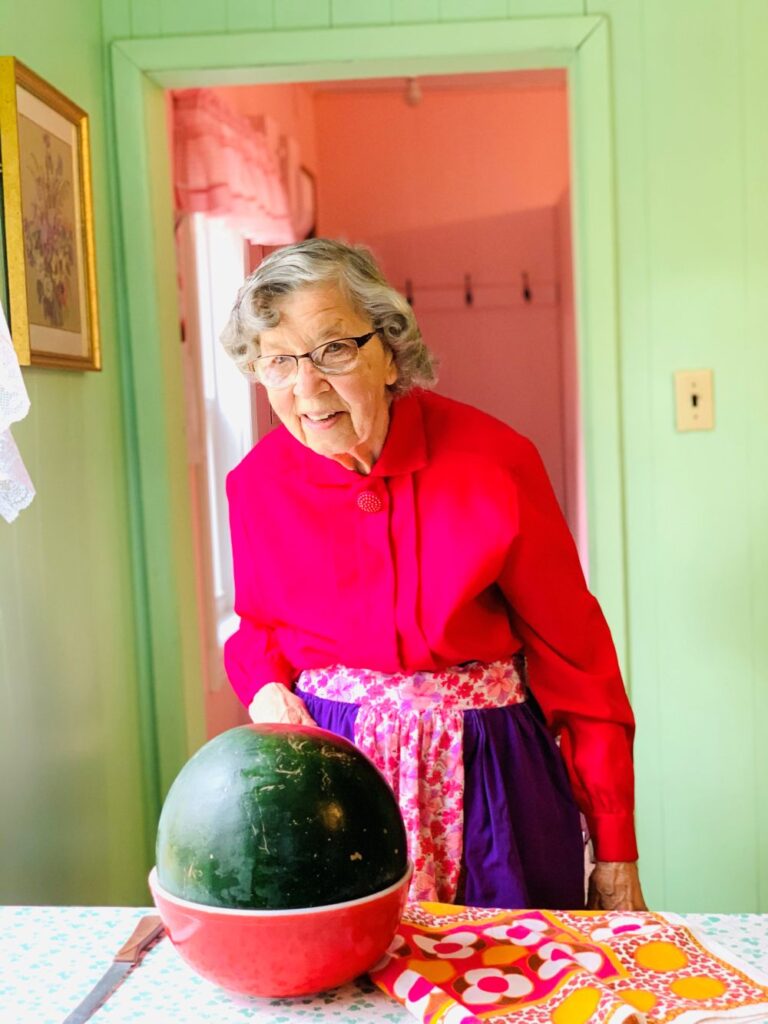 Agatha stands in front of a watermelon placed on a dinner table
