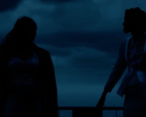 Two figures appear as black silhouettes against a darkened blue backdrop.