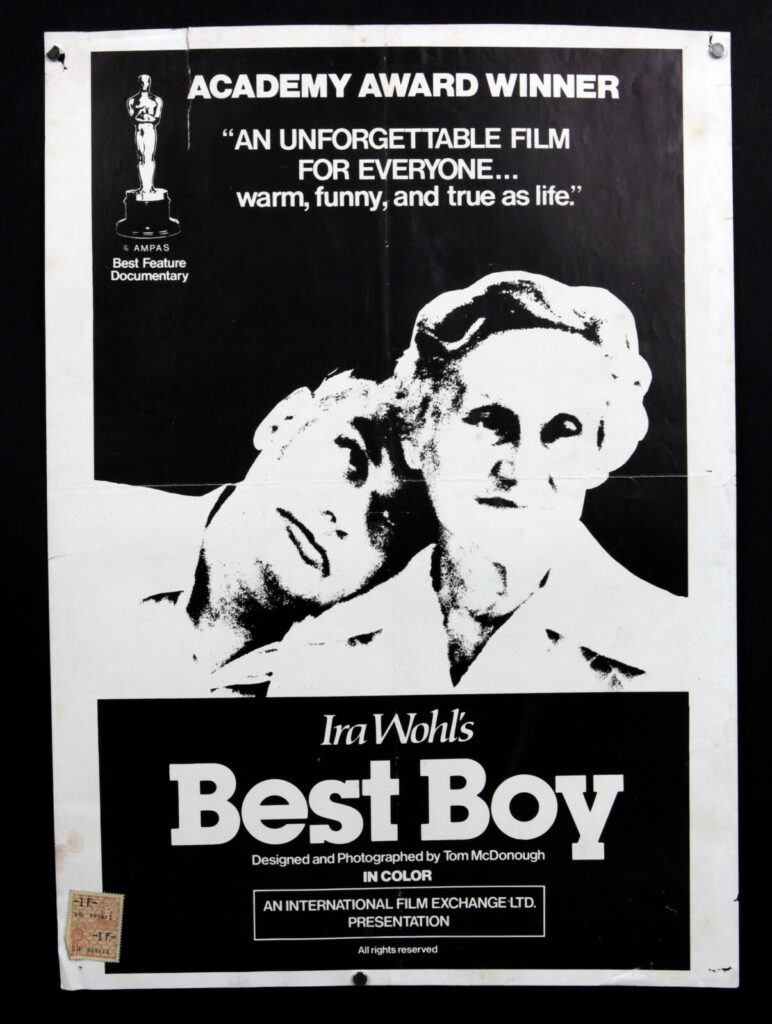 A black and white poster for the documentary best boy shows an adult male resting his head on his mother's shoulder.
