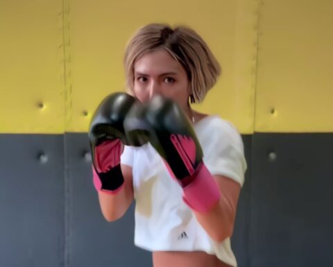 A young Afghan woman stands in a boxing stance with her fists raised, slightly obscuring her face.