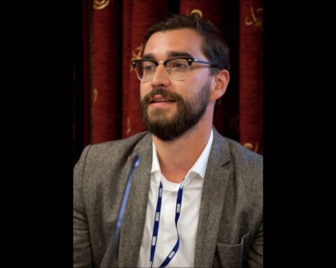 Gabor Pertic is a white man with brown hair and facial hair. He is pictured in close up at an industry event, wearing a grey blazer, white shirt, and glasses.