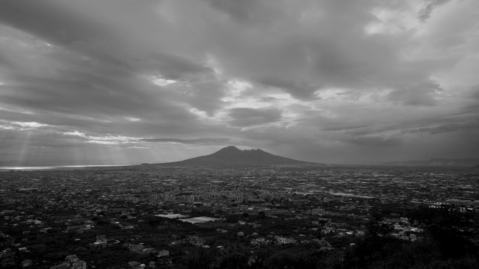 A black and white photo of Mount Vesuvius and the surrounding landscape of Naples, Italy.