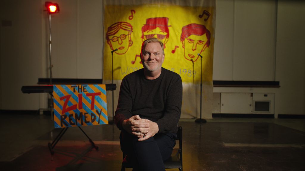 Actor Stefan Brogren sits in a classroom with Zit Remedy memorabilia from Degrassi. 
