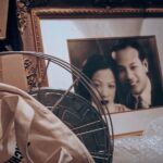 An sepia-toned photo of a picture frame containing a Chinese husband and wife on their wedding day.