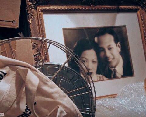 An sepia-toned photo of a picture frame containing a Chinese husband and wife on their wedding day.
