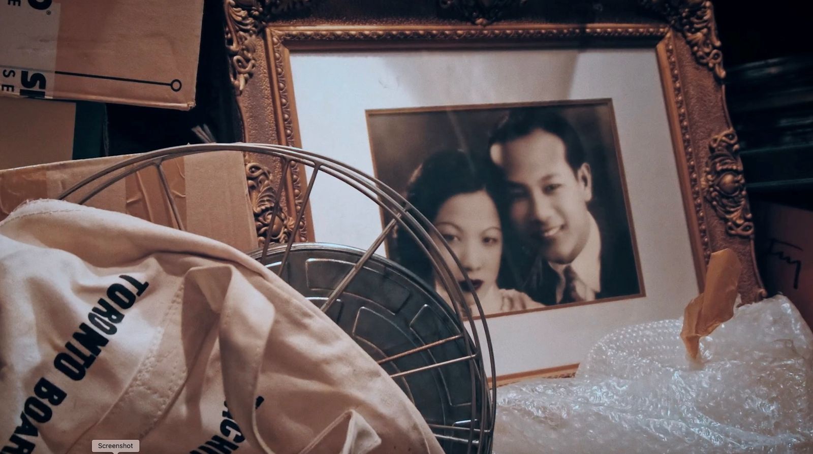 An sepia-toned photo of a picture frame containing a Chinese husband and wife on their wedding day.