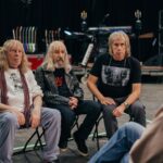 Three members of the rock band Spinal Tap, now in their 60s, sit on chairs in a recording studio
