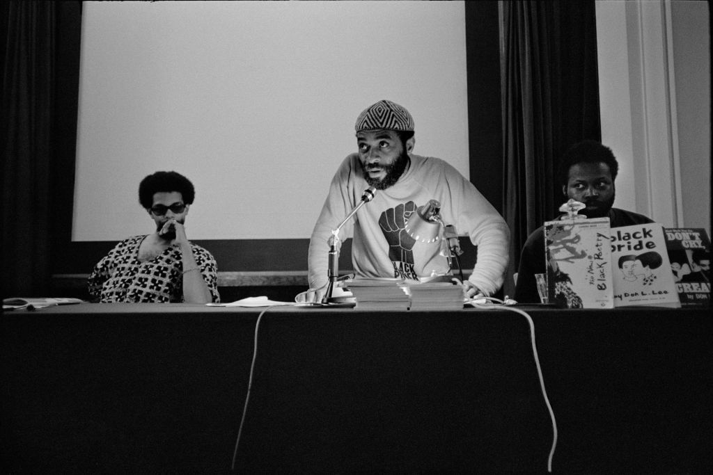 A black and white photo of a Black Power meeting from the 1960s with three Black men conducting a press conference.