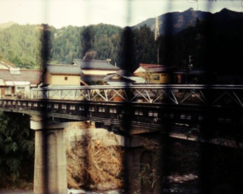 A vintage photograph of a bridge. There are black vertical lines patterning the photo