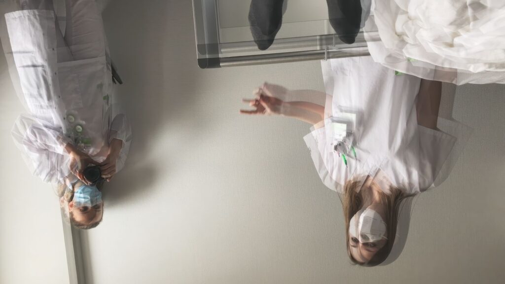 A point of view shot from a patient in a hospital bed, looking at two blurry doctors who are upside down.