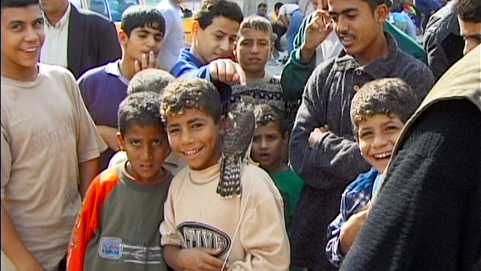 Children in Gaza pose for the camera and smile. The boy in the centre has a hawk on his shoulder.