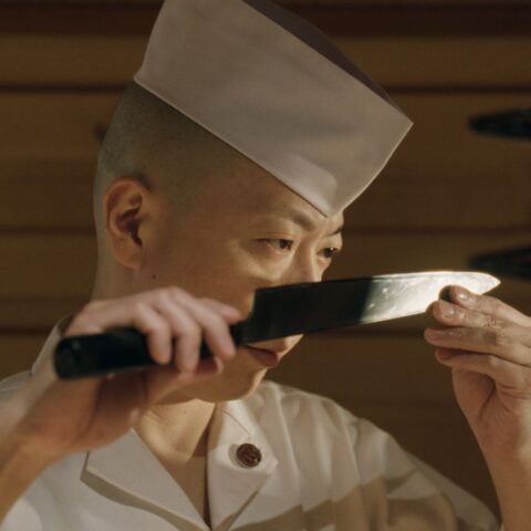 Chef Masaki Saito examines the blade on his knife.
