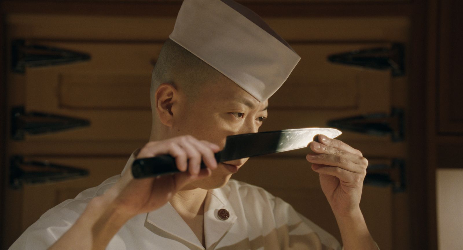 Chef Masaki Saito examines the blade on his knife.