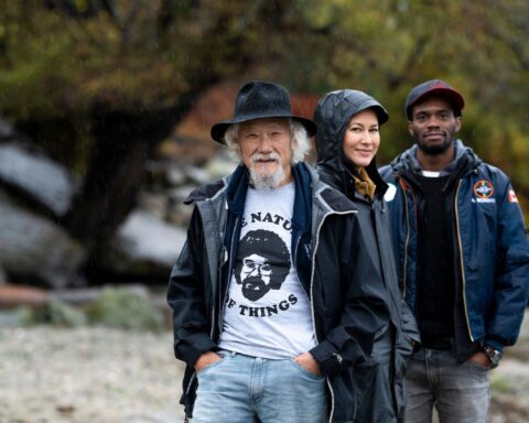 David Suzuki stands with Sarika Cullis-Suzuki and Anthony Morgan, the new generation of hosts for the Nature of Things. They are outside on a rainy day.