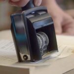 A close-up of a stamp pressing a date on an index card of a library book.