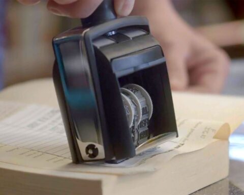 A close-up of a stamp pressing a date on an index card of a library book.