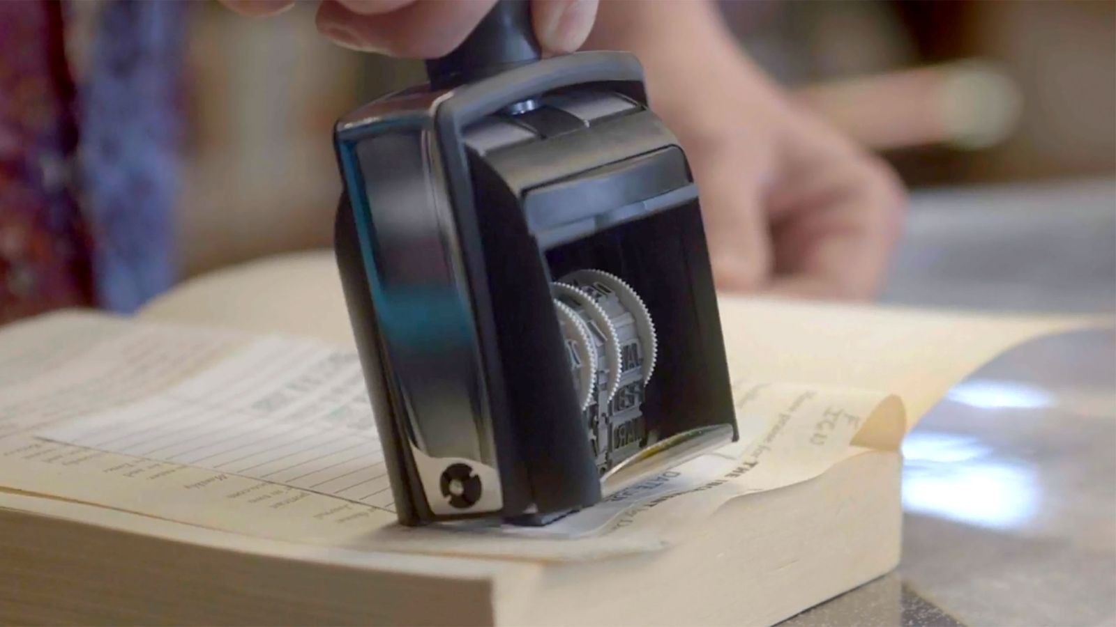 A close-up of a stamp pressing a date on an index card of a library book.