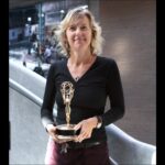 Tracey Friesen holding the Northwest Regional Emmy Award for Best Historical Documentary for the film Mighty Jerome in front of the NFB’s Vancouver studio in September 2012.
