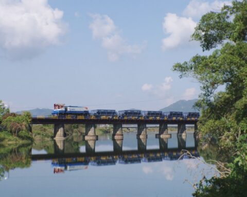 A train crosses a bridge that stretches over a river.