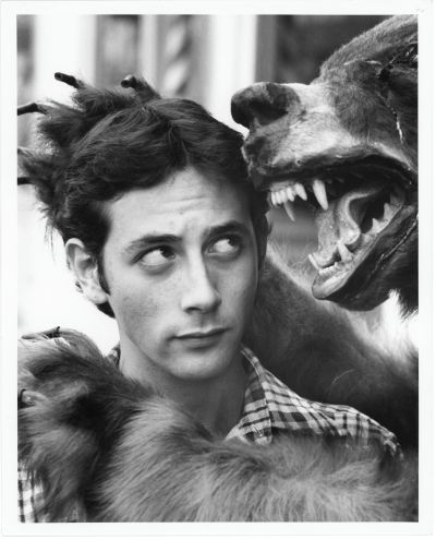 A black and white photo of Paul Reubens looking up at a stuffed bear.