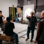 Filmmaker Ron Mann directors a documentary film crew on a sound stage.