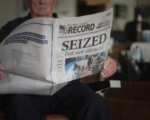 A man reads a newspaper with the headline 'Seized...but not silenced'