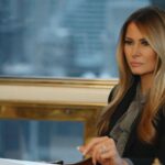Melania Trump sits at a desk.