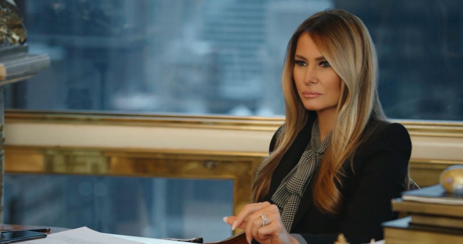 Melania Trump sits at a desk.