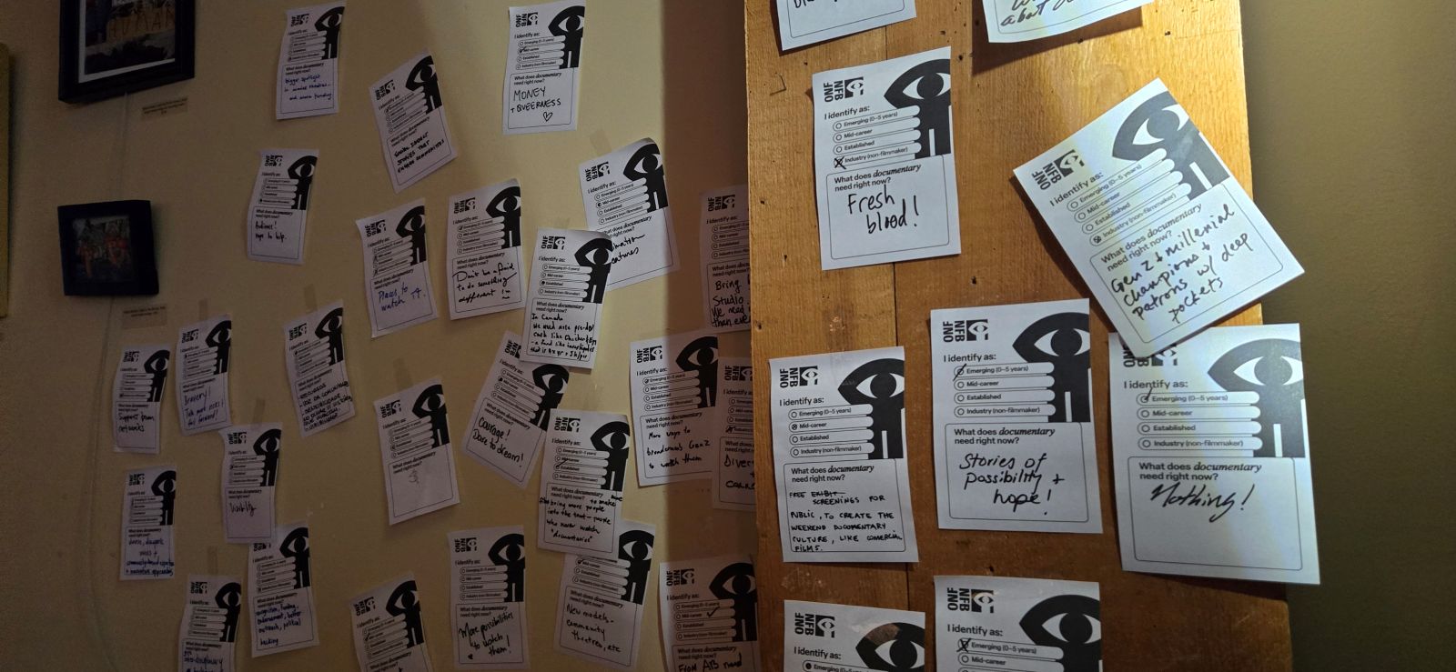 A series of white pieces of paper taped to a wall. They have the NFB logo in the top right corner and various messages scribbled in black marker.