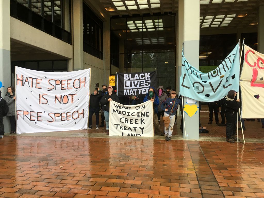 A series of protest placards with slogans including "hate speech is not free speech."