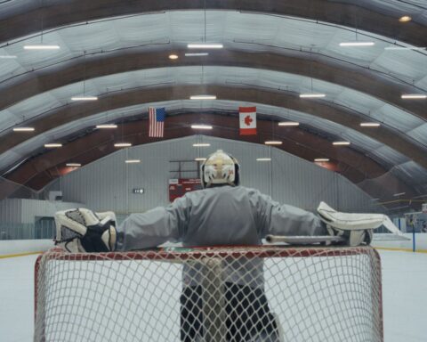 A lone goalie waits for teammates to take the ice during a pickup game in London, Ontario.