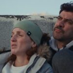 A Palestinian husband and wife lean in close together while looking up towards the sky.