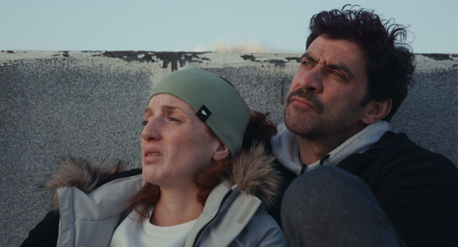 A Palestinian husband and wife lean in close together while looking up towards the sky.