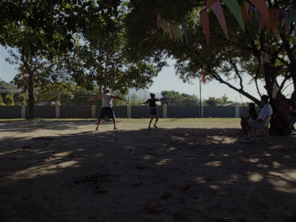 Lydia and Almario exercise under the intense morning sun as Serville carefully supervises,while Ruth looks on — a humorous moment that reflects the film’s warmth and care within everyday routines.