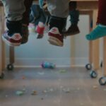 children's legs dangle beneath their desks in a classroom.