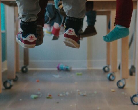 children's legs dangle beneath their desks in a classroom.
